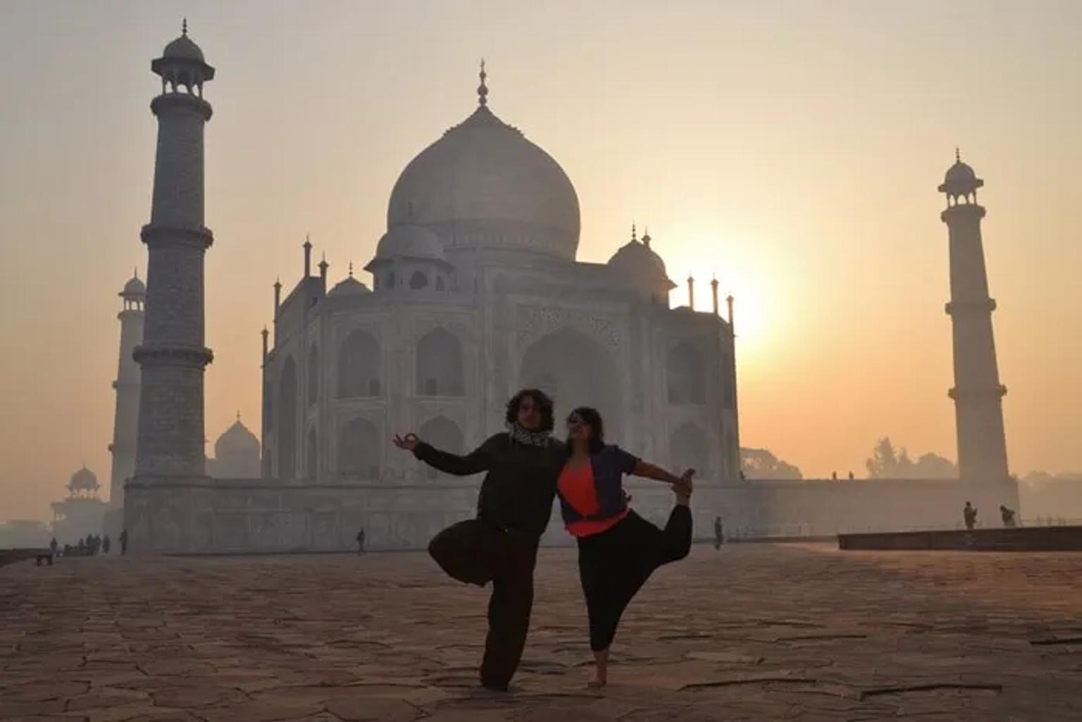 Pareja posando frente al Taj Mahal al amanecer, con siluetas marcadas.
