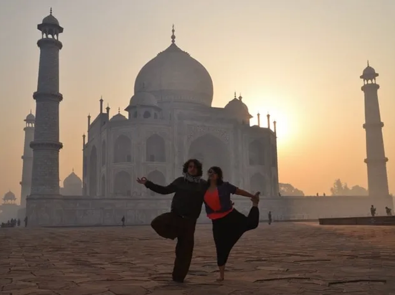 Pareja posando frente al Taj Mahal al amanecer, con siluetas marcadas.