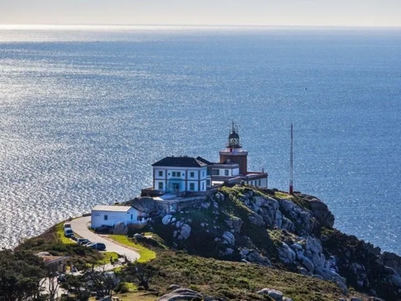 Faro y hotel en un acantilado, con vista al mar brillante.