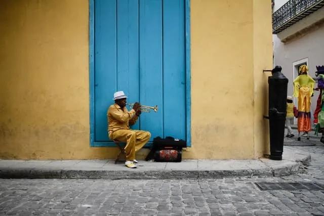 senhor sentado numa rua em Havana (cuba) a tocar trompete 