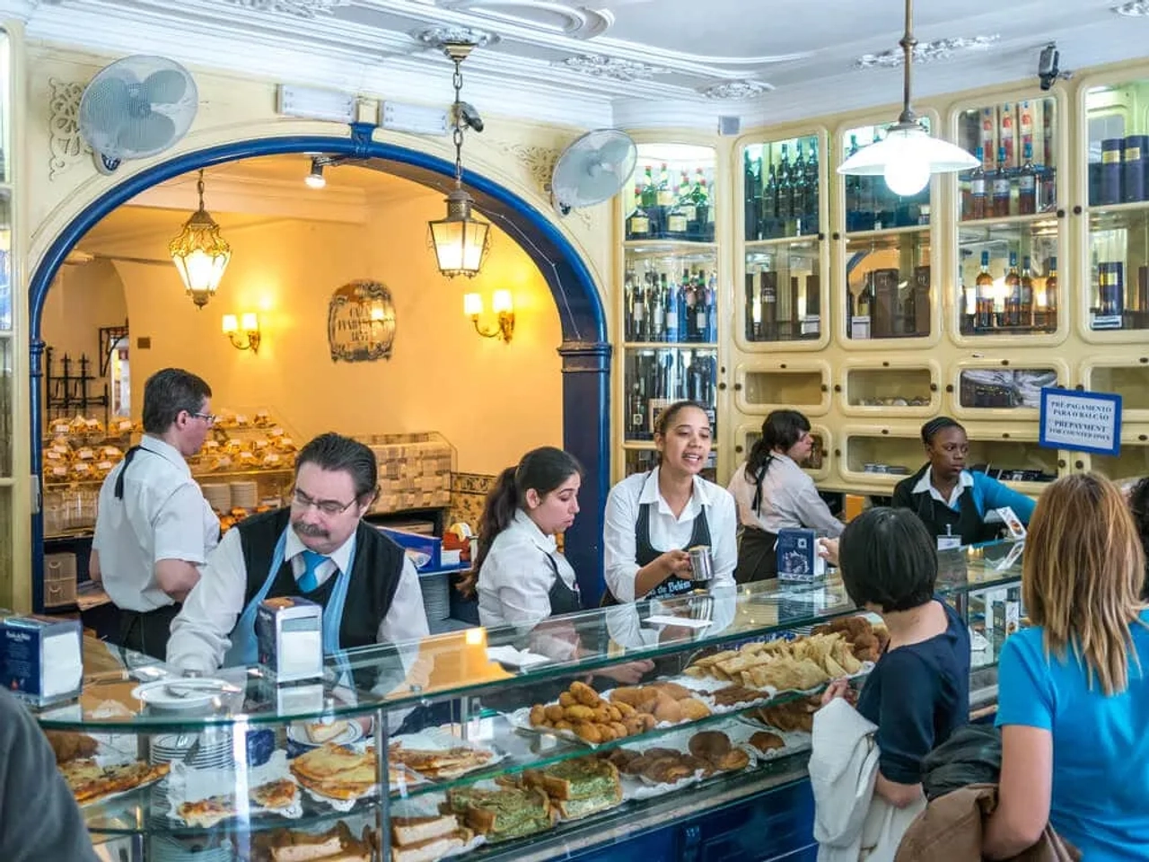 pessoas a comprar pasteis de belem ao balcao da pastelaria
