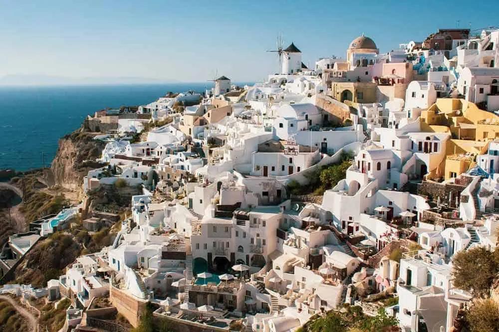 Vista panorâmica de casas brancas em Santorini, Grécia, com mar ao fundo.