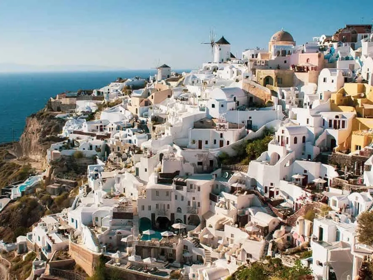 Vista panorâmica de casas brancas em Santorini, Grécia, com mar ao fundo.