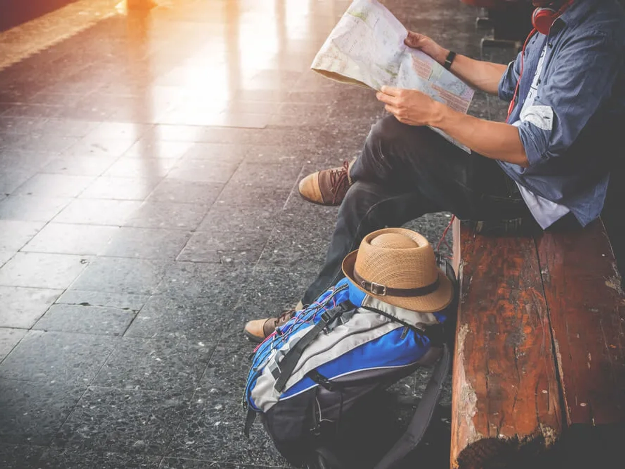 rapaz jovem sentado num banco com mochila ao lado