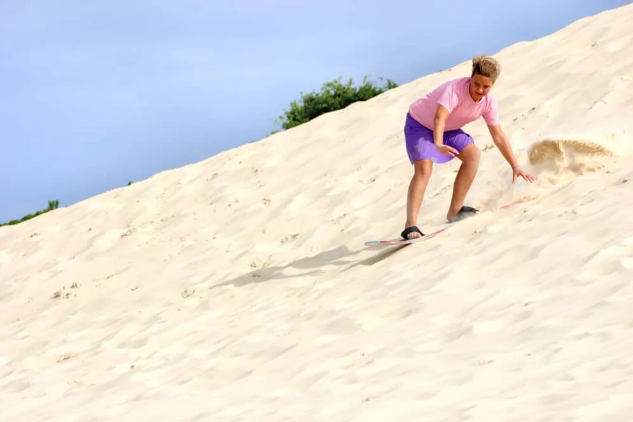 rapaz numa duna a praticar sandboard