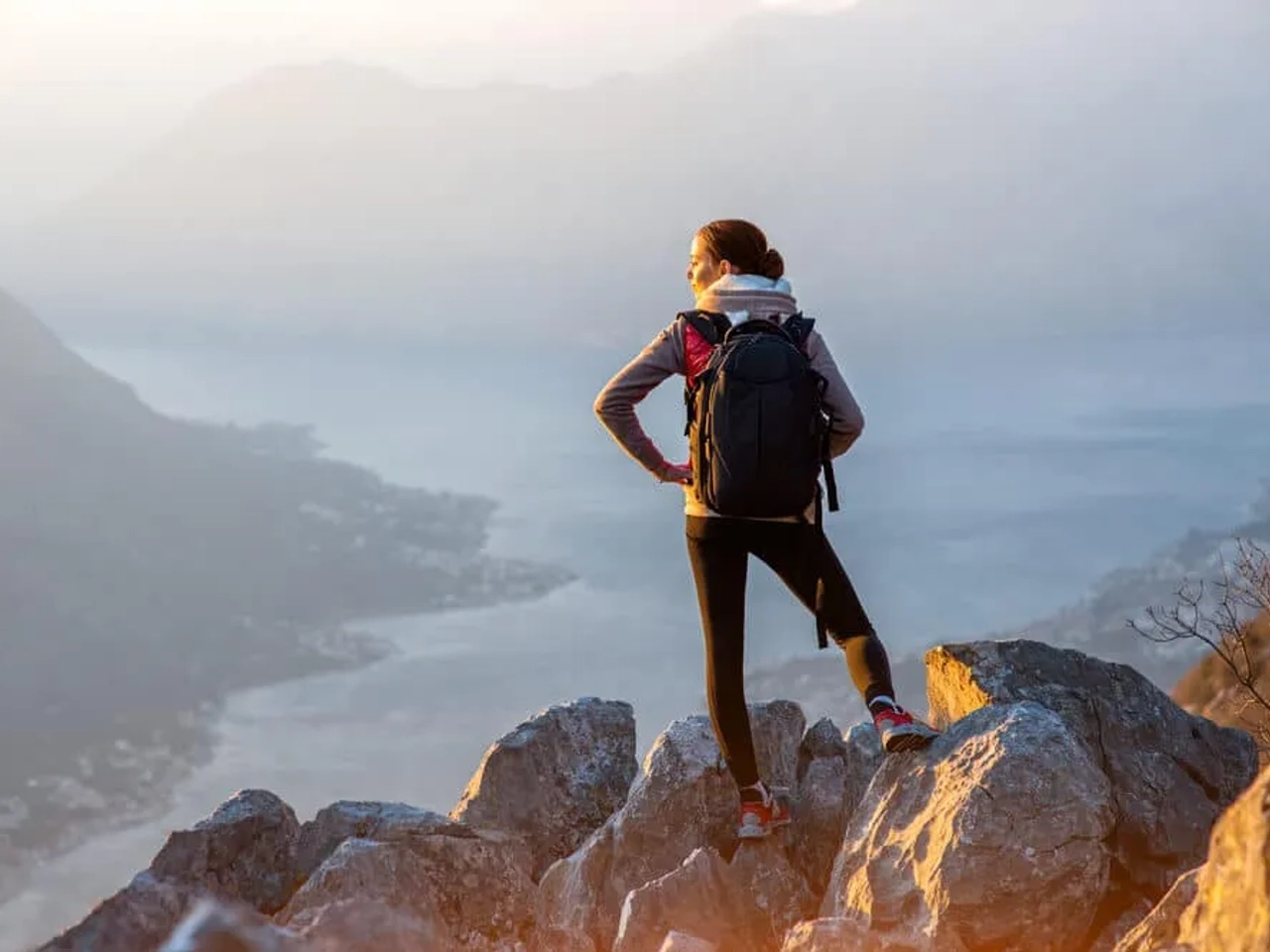 mulher no topo de uma montanha observa as vistas