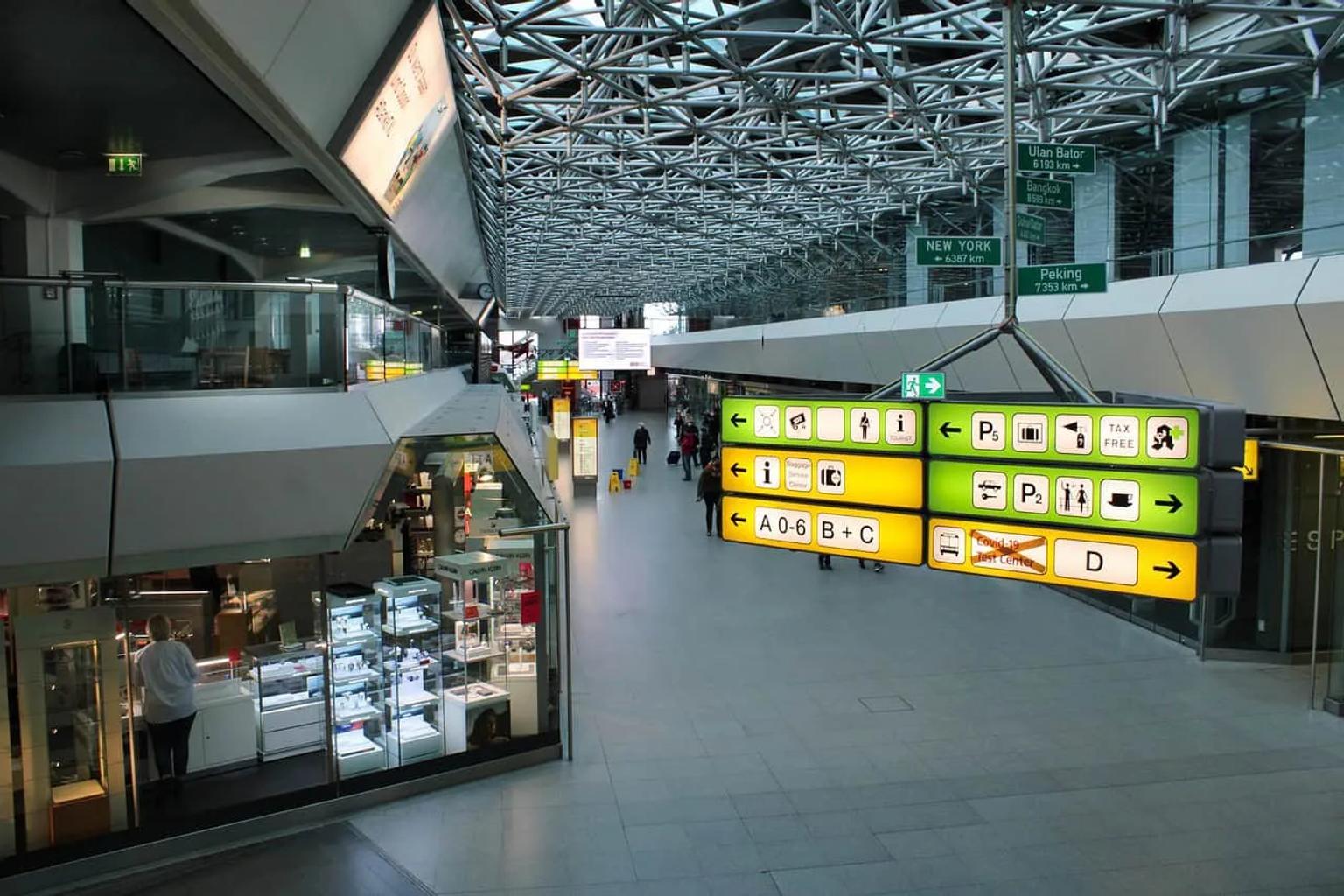 Aeropuerto moderno con señalización clara y tiendas visibles en el interior.