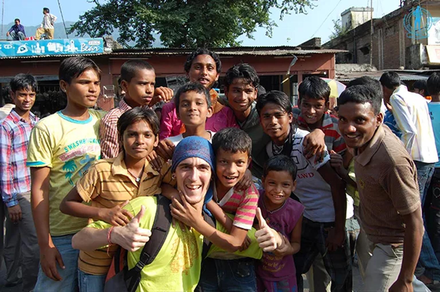Un grupo de niños sonrientes posando con un viajero en un entorno urbano.