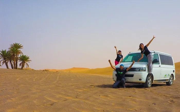 Familia feliz posando junto a una furgoneta en un desierto.