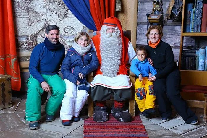 Familia viajera posando con Santa Claus en un ambiente invernal.