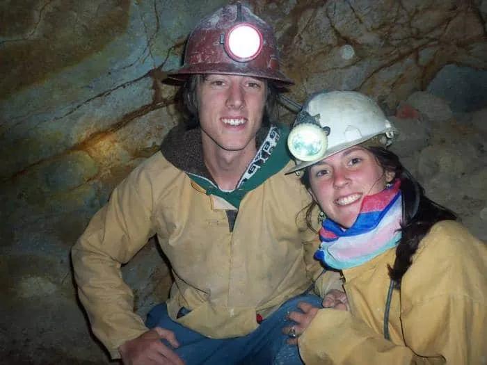 Pareja de viajeros en una mina, usando cascos y ropa de trabajo.