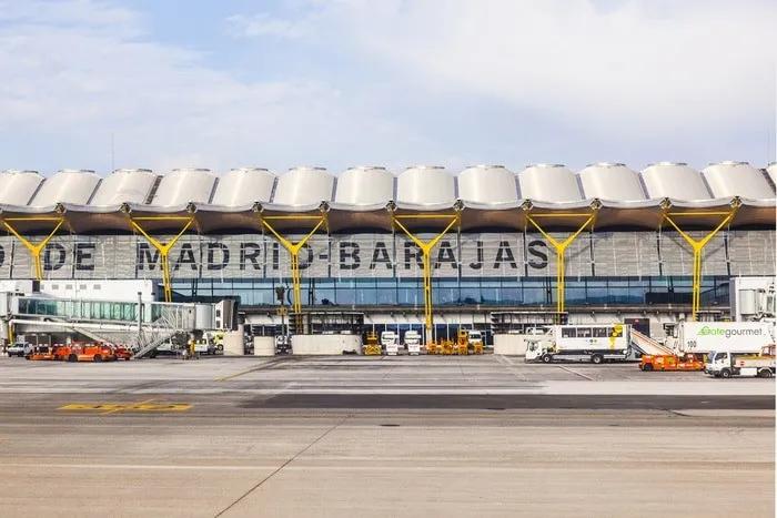 Edificio del aeropuerto de Madrid-Barajas con aviones y vehículos de servicio.