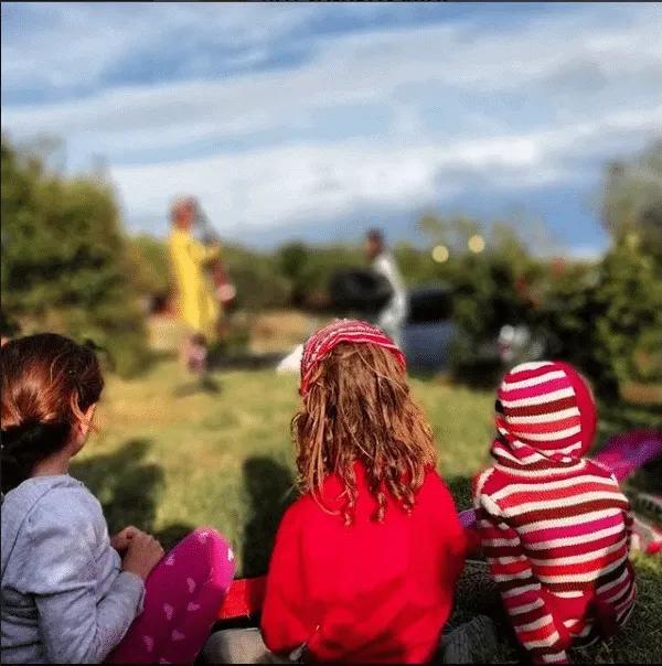 Niños observando una actuación al aire libre en un evento familiar.