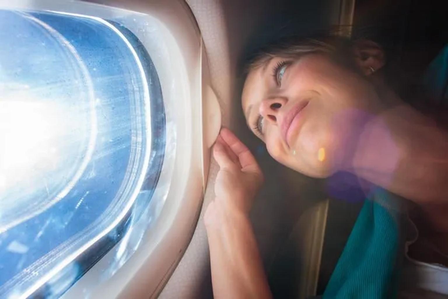 Mujer mirando por la ventana de un avión, disfrutando del paisaje.
