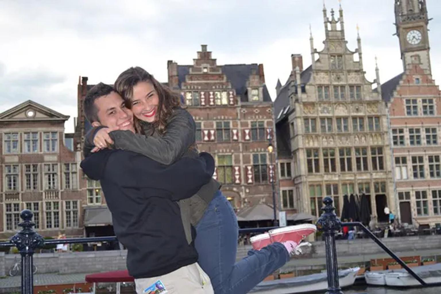 Pareja sonriente abrazándose frente a edificios históricos en Europa.