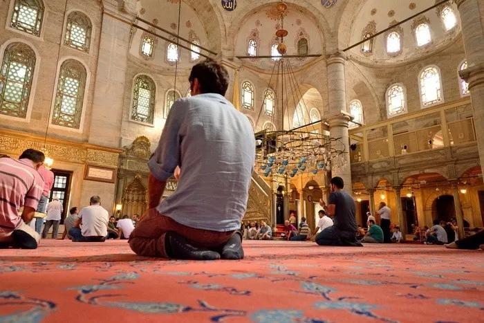 Interior de una mezquita en Estambul, con personas orando en el suelo.