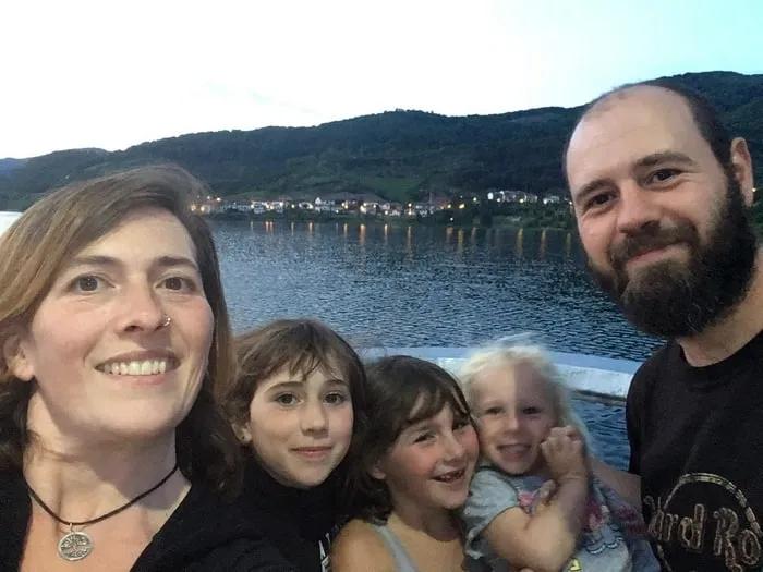 Familia sonriente en un paisaje junto al agua al atardecer.