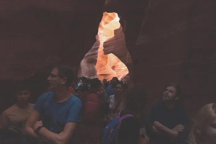 Grupo de personas en un cañón con formaciones rocosas iluminadas.