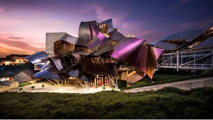 Hotel con diseño arquitectónico innovador y colorido, rodeado de vegetación.