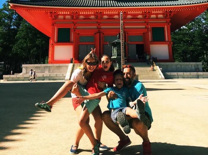 Familia sonriente frente a un templo rojo, disfrutando de un día de verano.