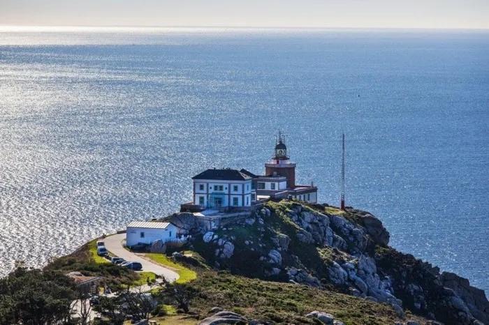 Faro y hotel en un acantilado, con vista al mar brillante.