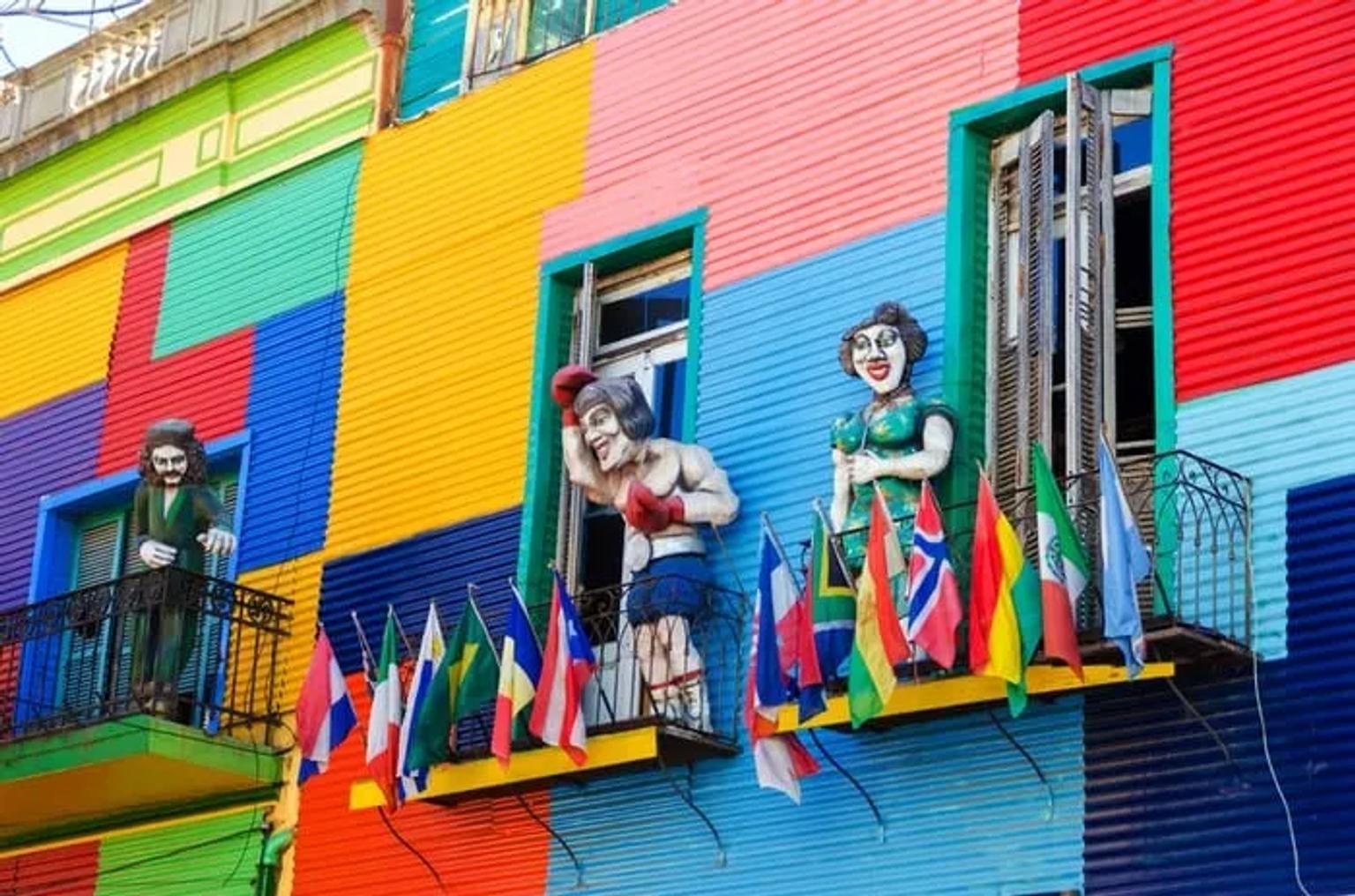 Fachada colorida con estatuas y banderas en un barrio de Sudamérica.