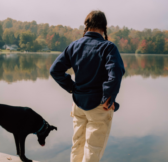 woman stood with a dog overlooking the river