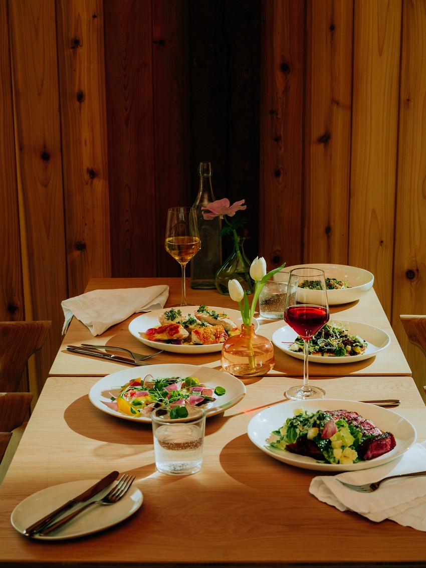 a table filled with plates of food, cutlery, and a glass of wine