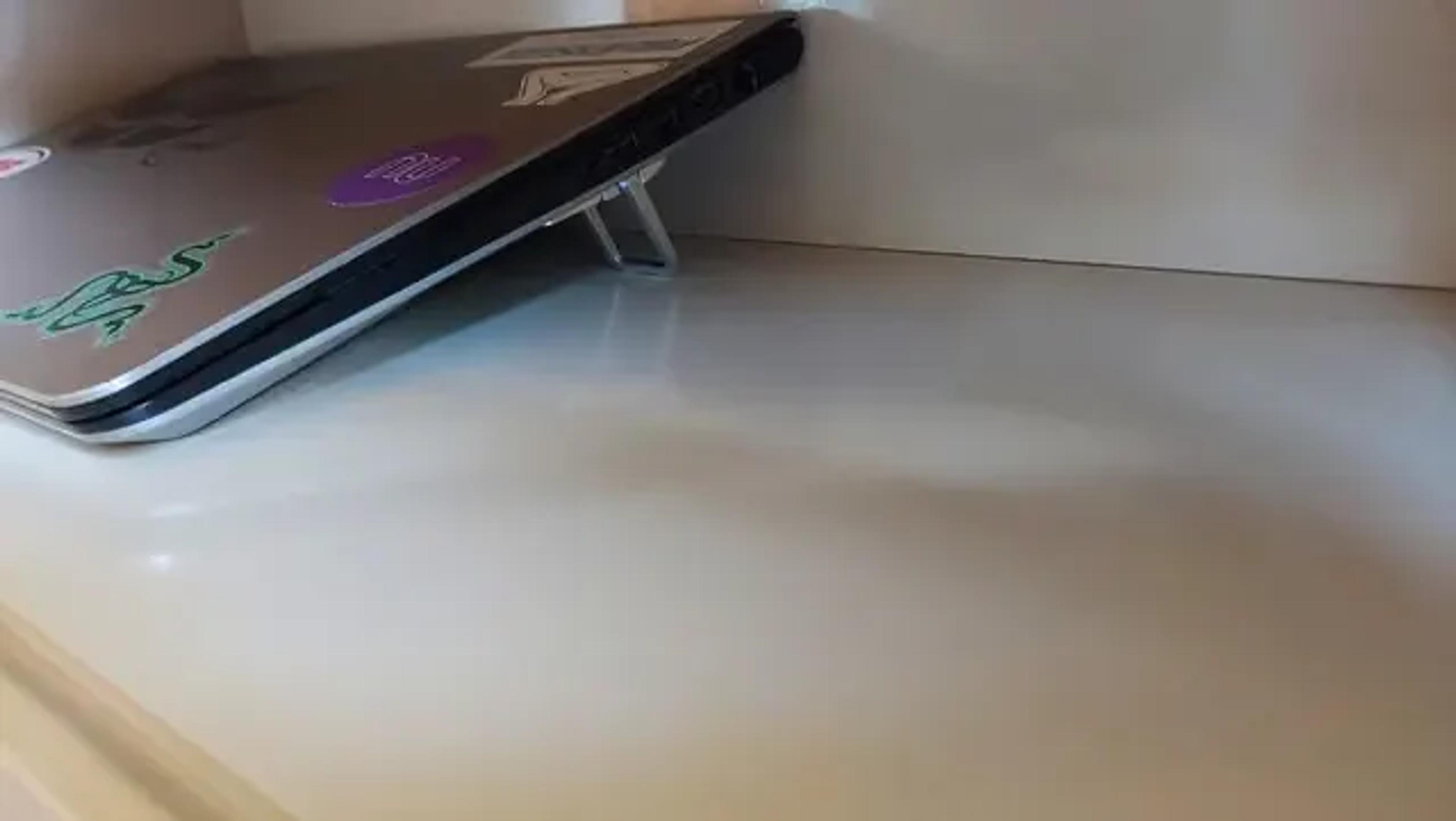 Notebook reaproveitado sobre uma prateleira, elevado por pés dobráveis