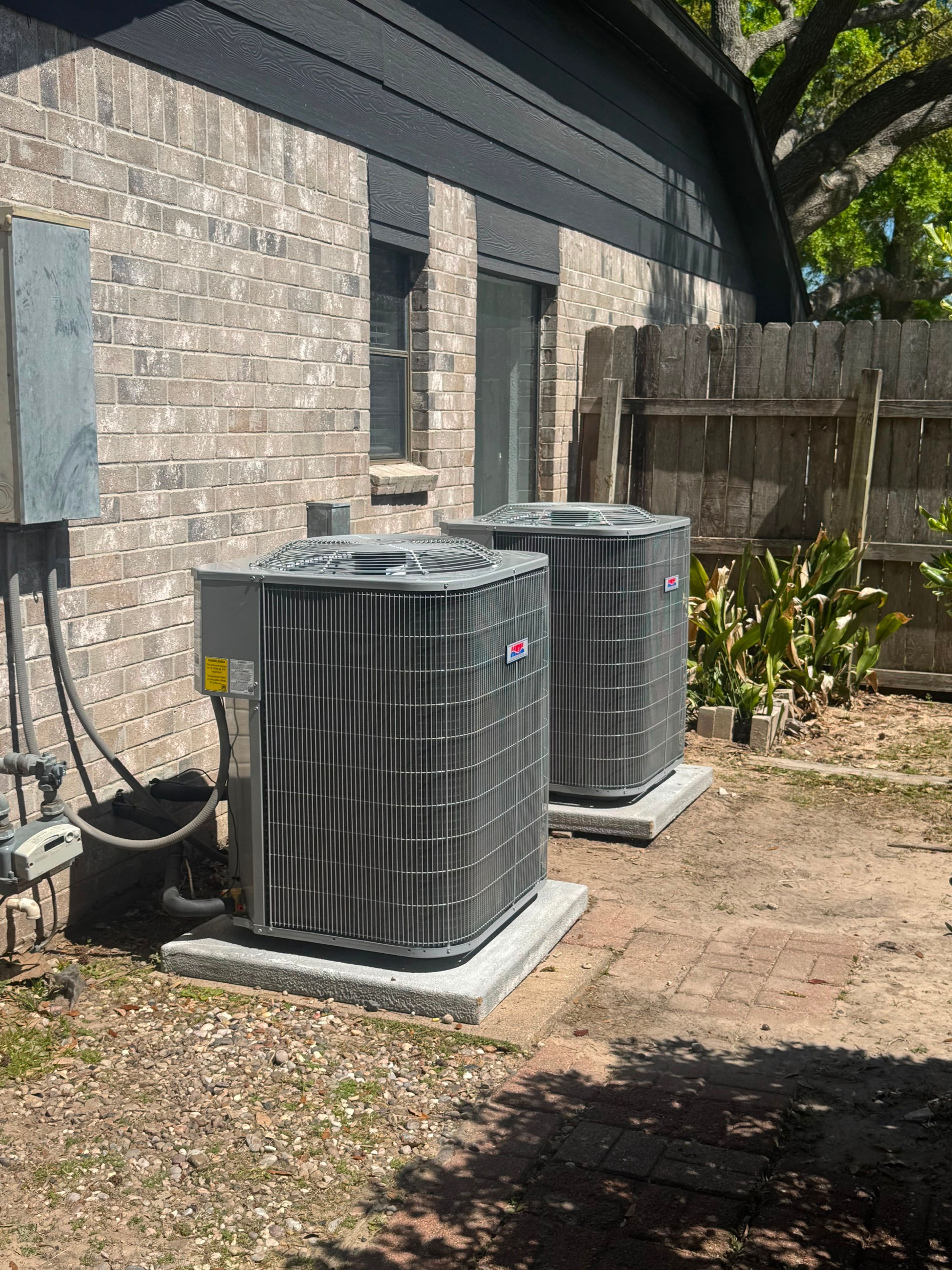 Two newly installed air conditioning condensers beside a Baytown home