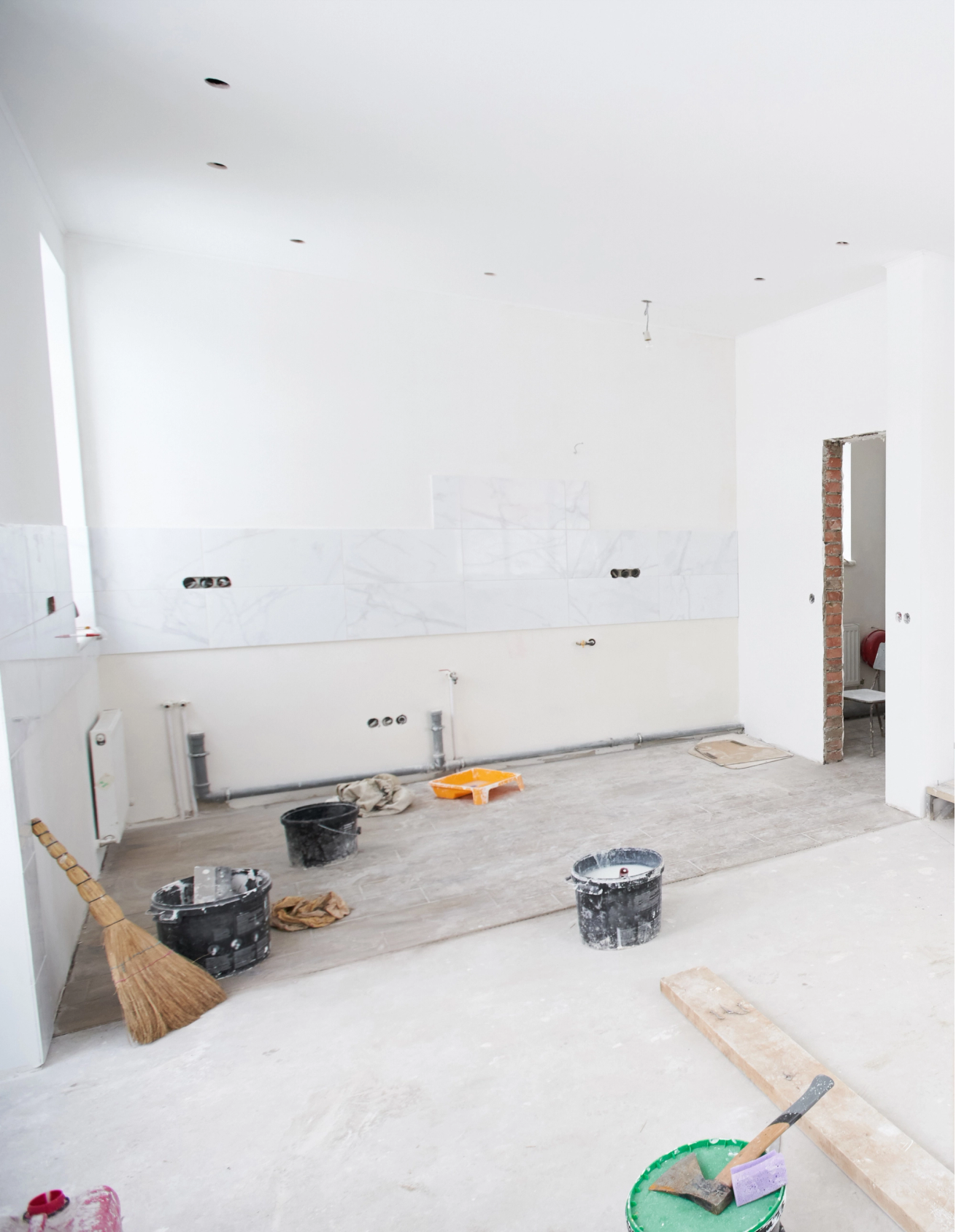 Unfinished, under renovation with construction tools, exposed wiring, and partially installed marble-patterned tiles.