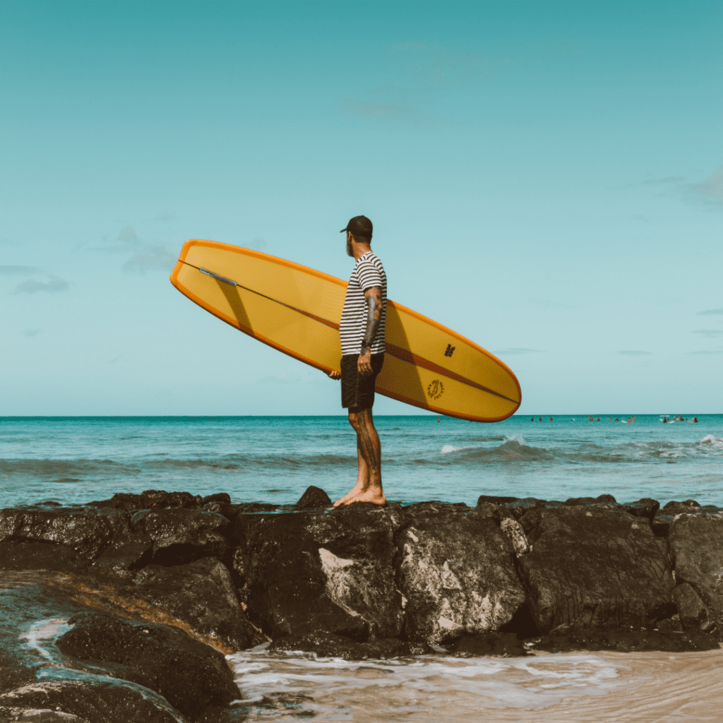 2022 Hawaii State Art Museum RFP Man holding a surf board image uploaded for The Bid Lab's Featured Bid Marketing of Hawaii State Art Museum RFP.