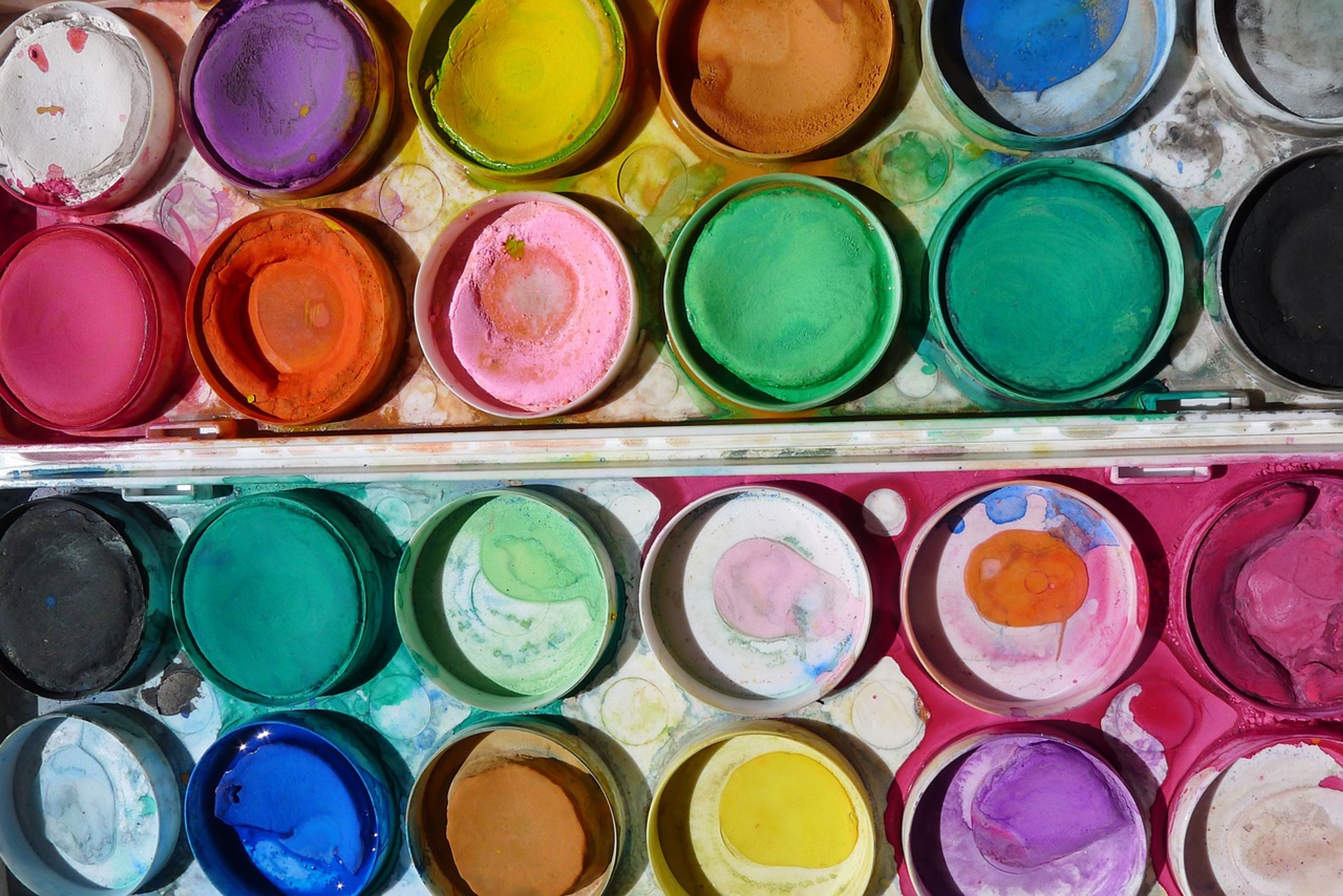 An open box of watercolor paints, containing many different colors