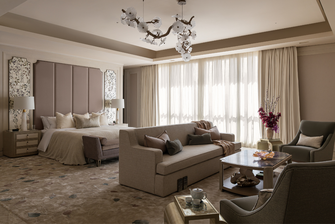 Dubai family villa master bedroom with upholstered headboard, soft neutral furnishings, layered seating and filtered daylight.