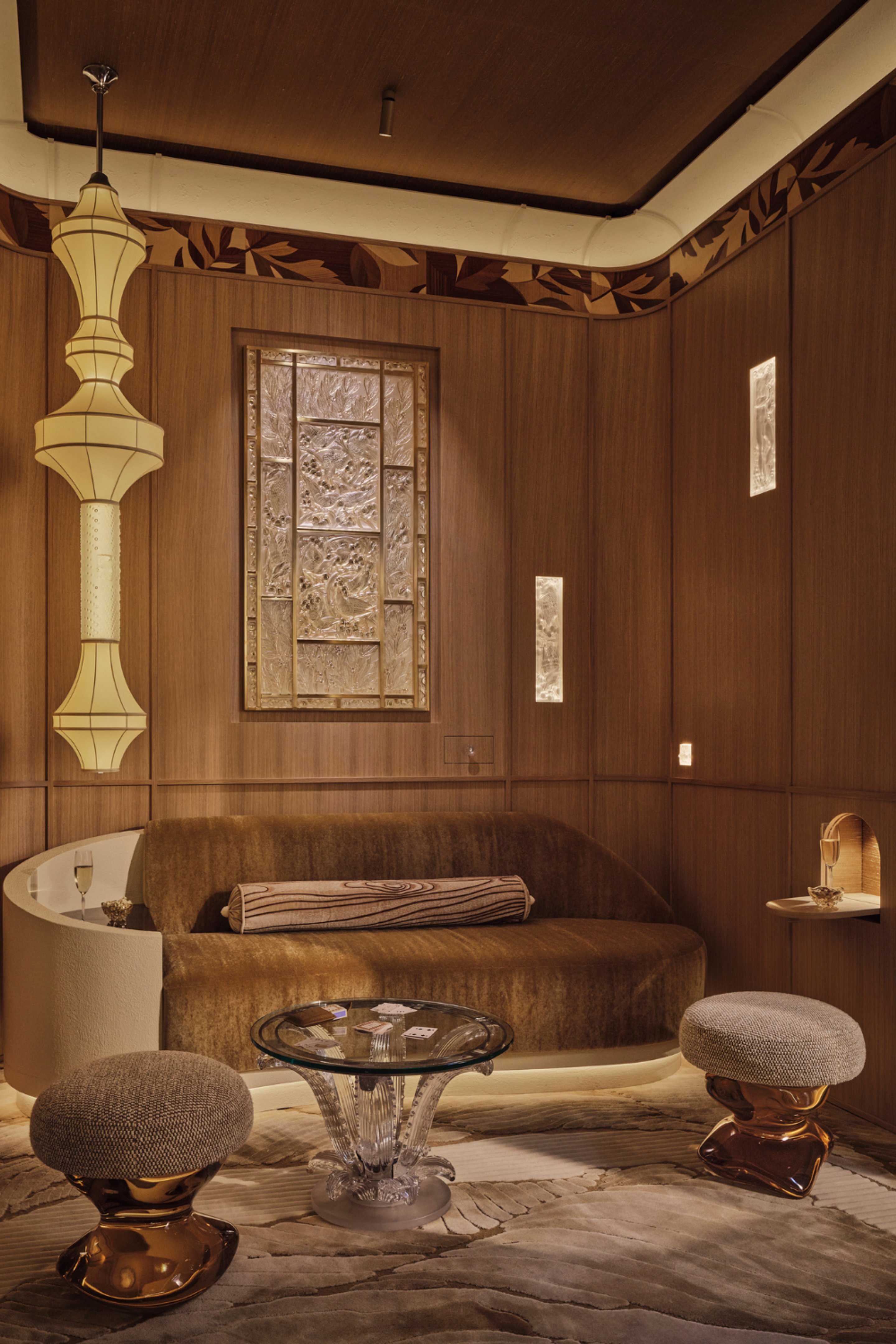 Art Deco-inspired lounge by Elicyon featuring warm timber panelling, sculptural lighting, custom furniture and decorative glasswork.