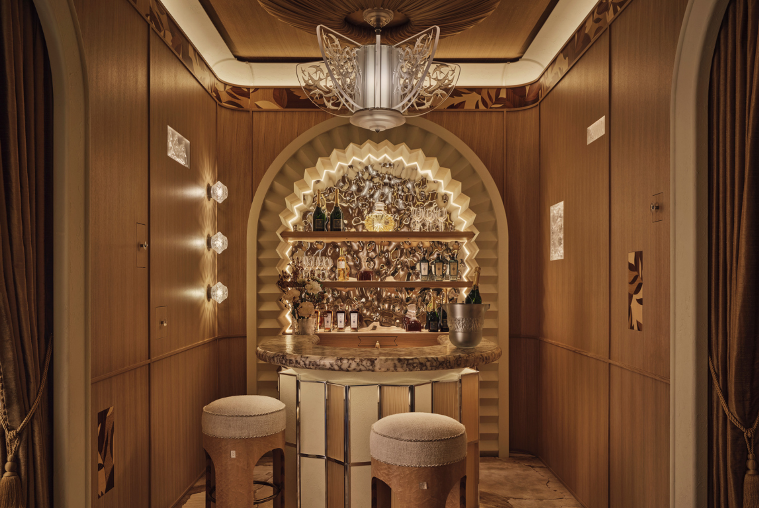 Art Deco-inspired private bar with sculptural lighting, warm timber panelling and a marble counter, designed by Elicyon.