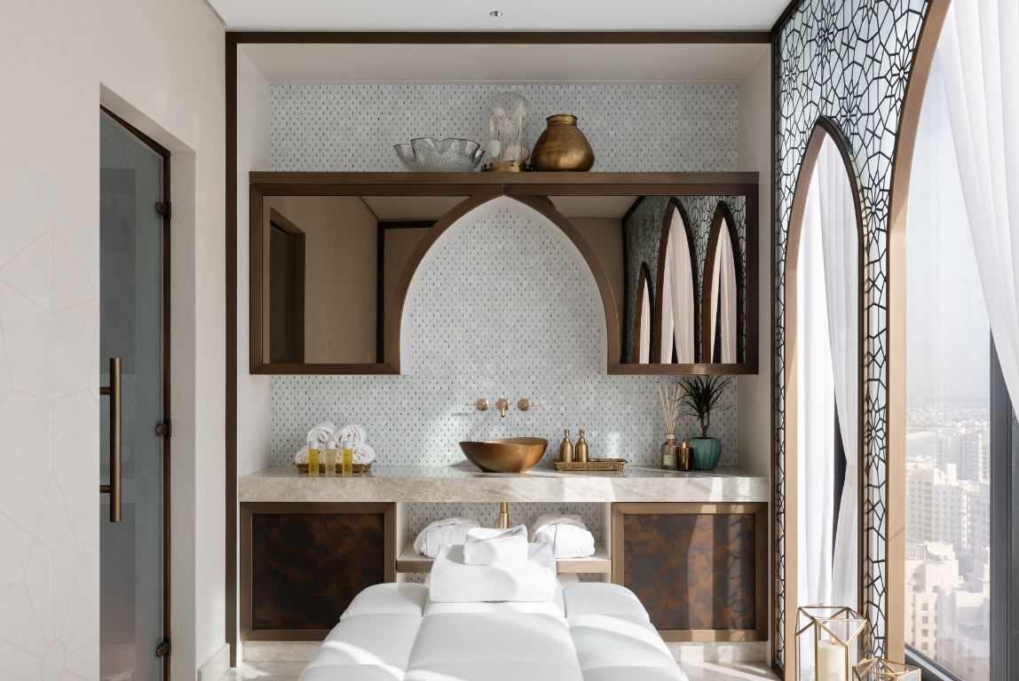 Private spa treatment room with arched mirrored joinery, brass detailing and city views framed by decorative screens.