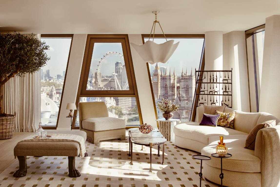Curved seating and sculptural lighting frame panoramic London views, with the London Eye and Westminster beyond angled glazing.
