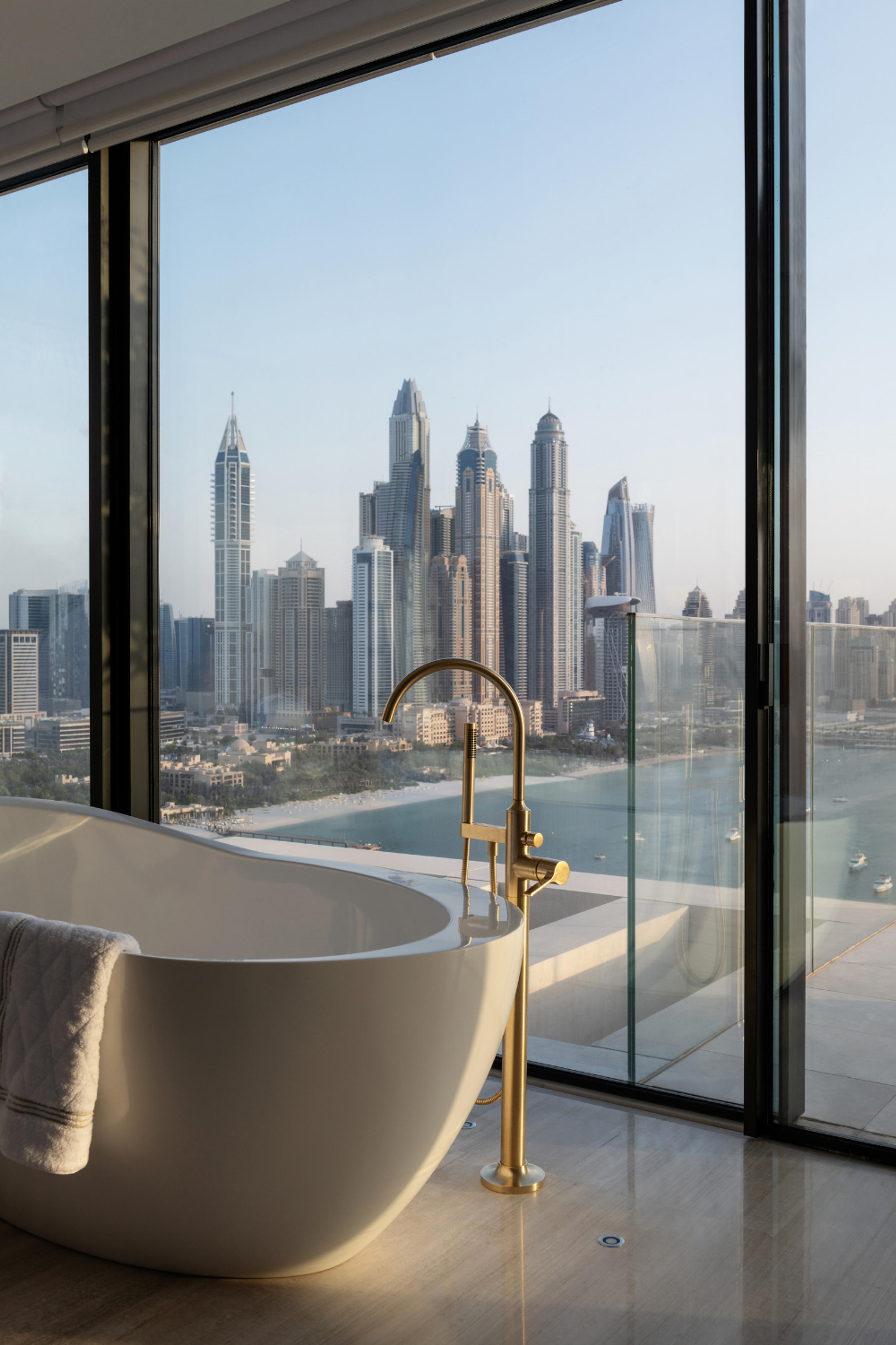 Freestanding bath with brass tapware overlooking Dubai Marina skyline in a luxury Dubai Penthouse.