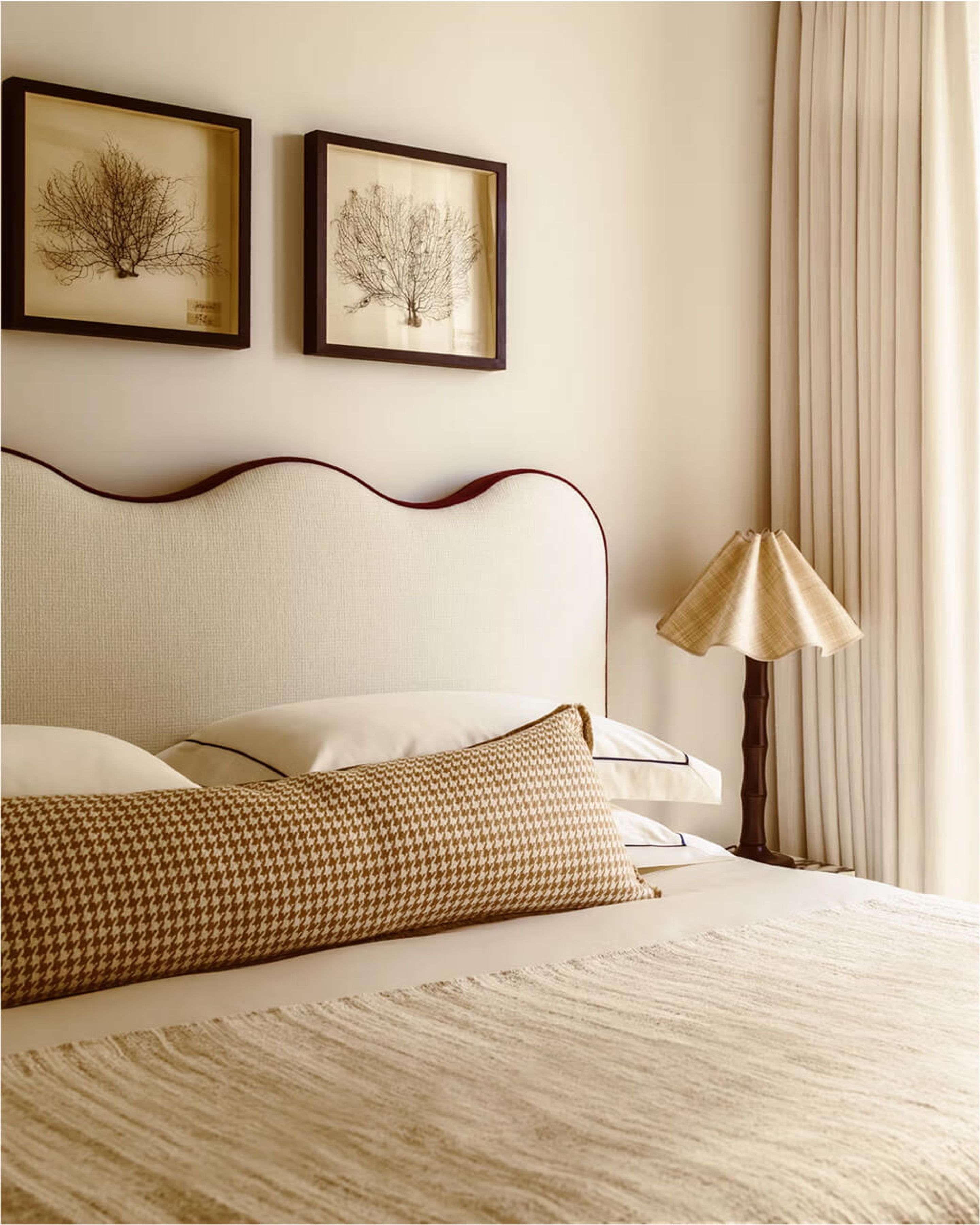 A close up shot of a bed, wall art, and a lamp.