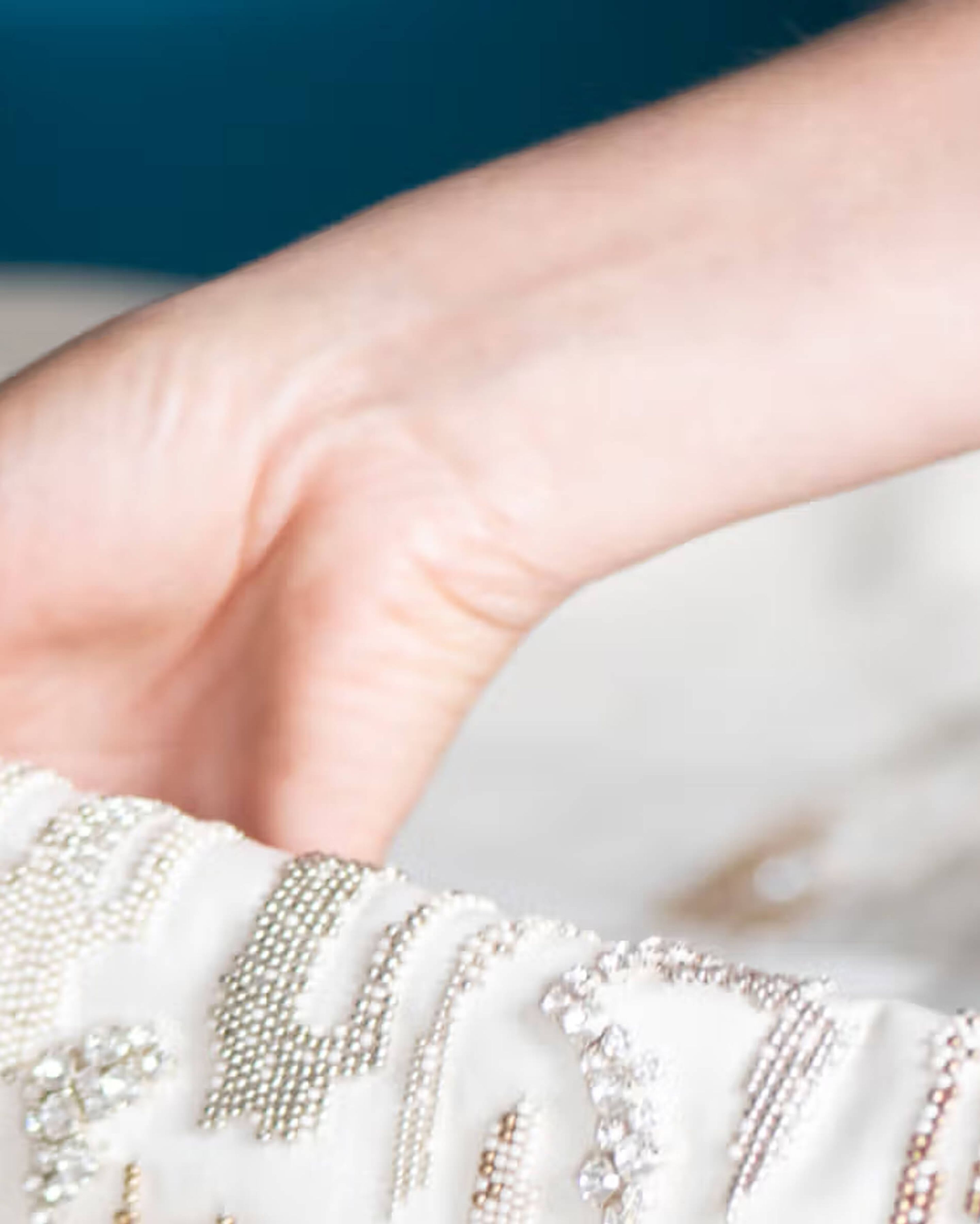 A close up of someone holding fabric with beaded detail.
