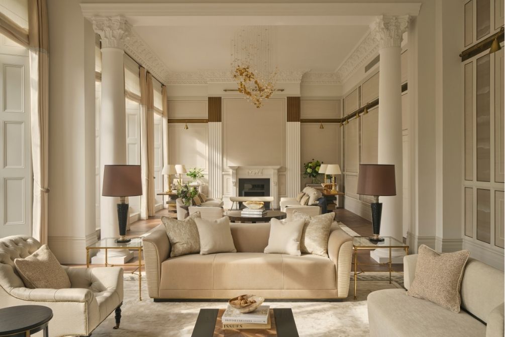 Elegant reception room featuring classical columns, decorative cornicing, neutral upholstered seating and a statement chandelier.