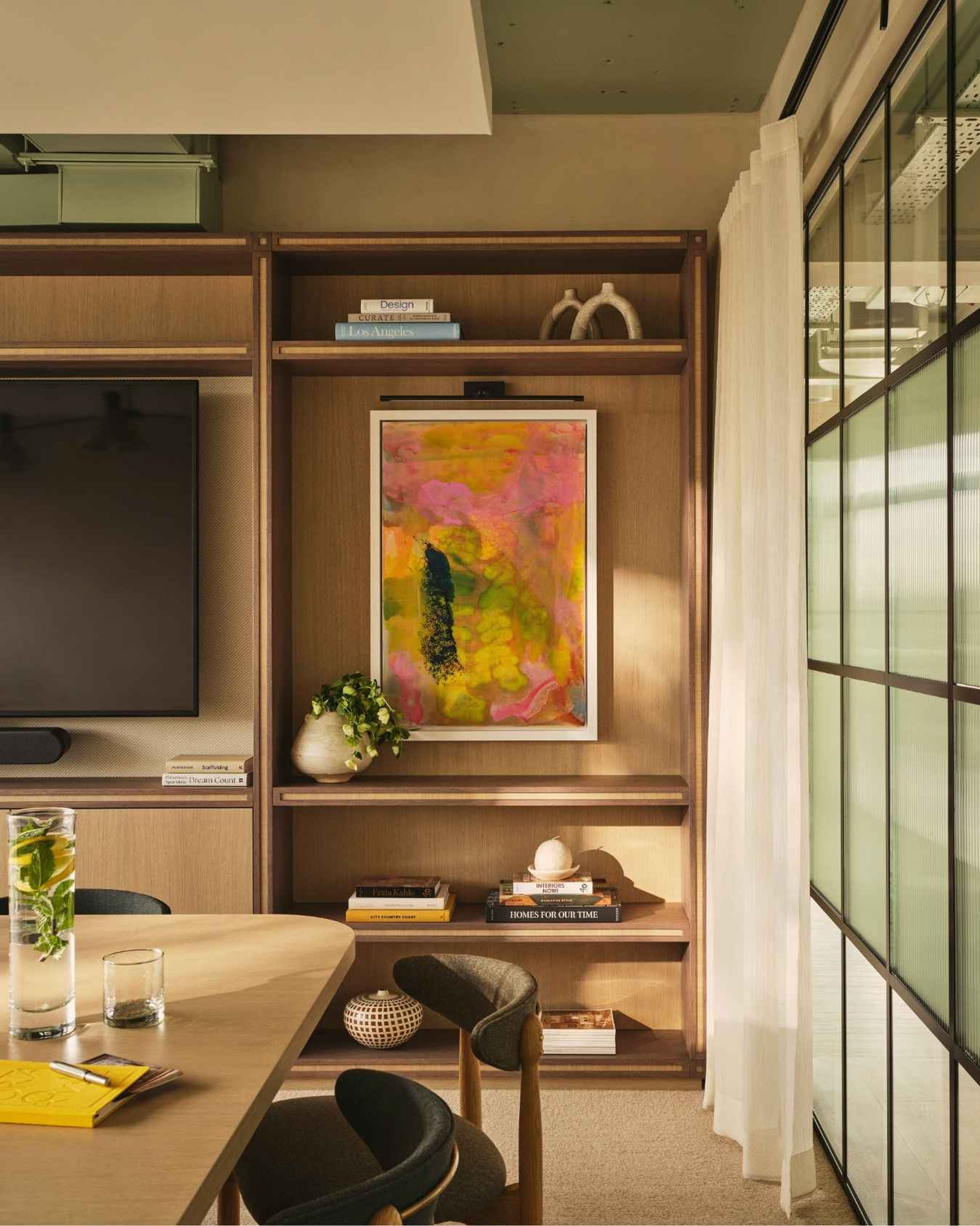 Bespoke timber shelving with colourful abstract artwork, curated accessories and contemporary meeting room furniture.