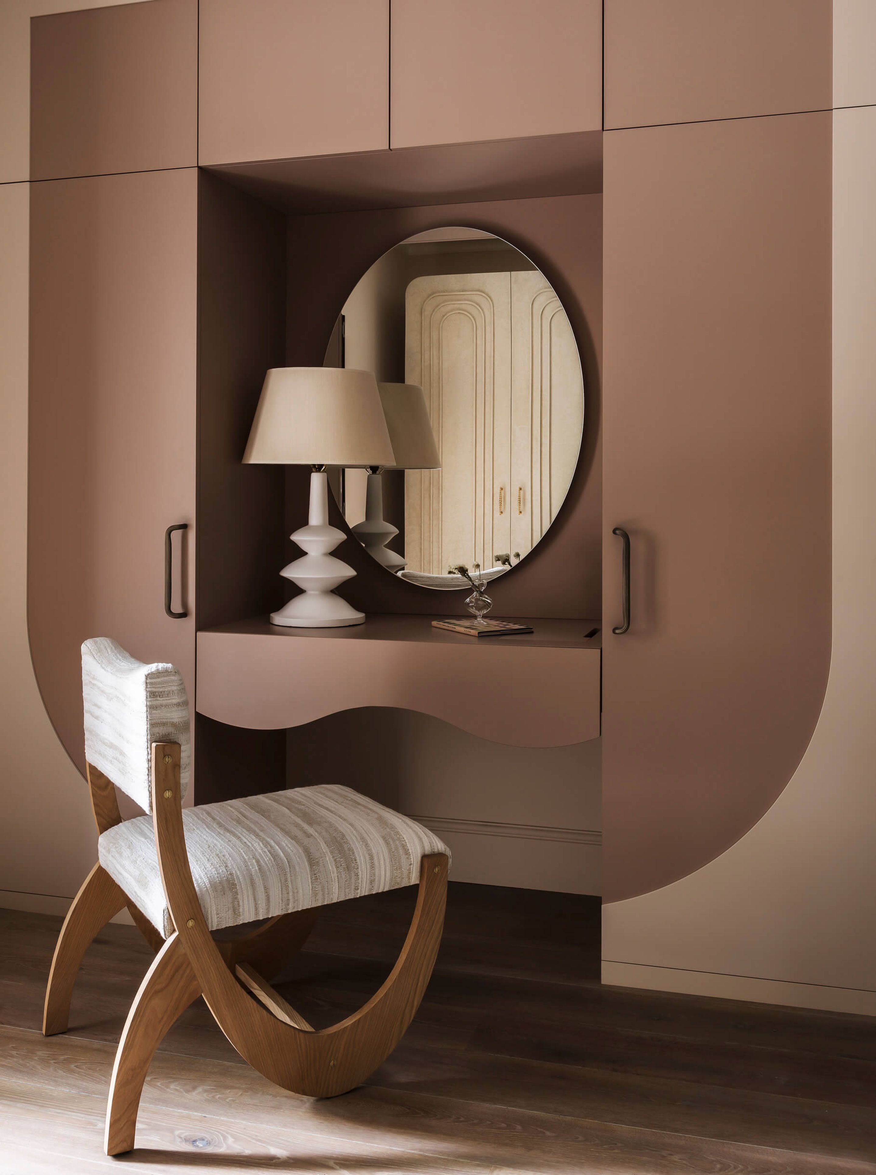 A bench built into the wall with a mirror and a chair