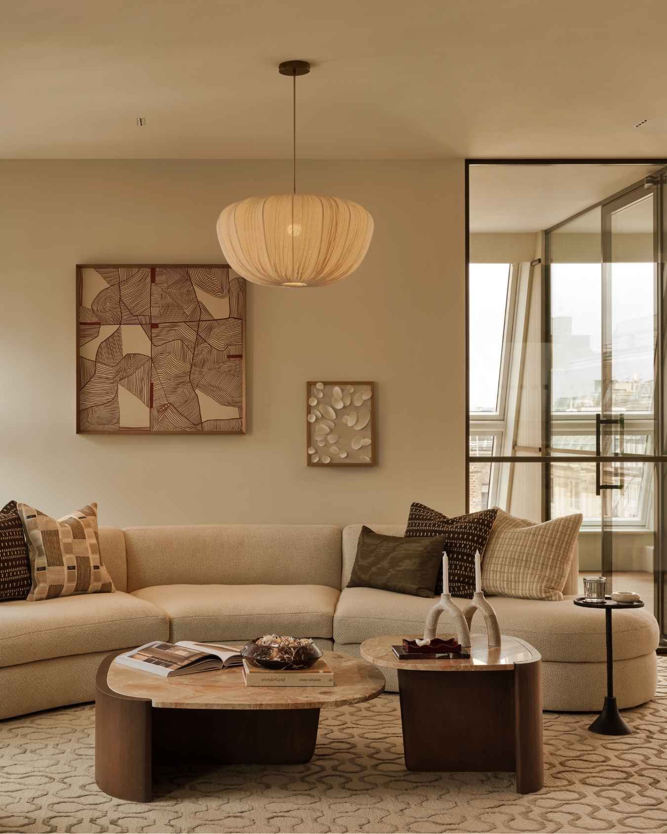 Elegant contemporary lounge with curved cream sofa, sculptural coffee tables, textured rug and statement pendant lighting.