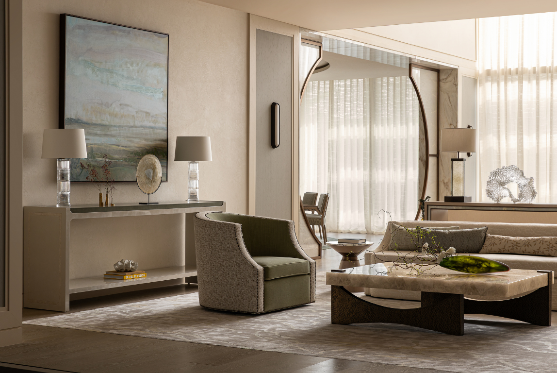 A calm living space with neutral tones, featuring a sculptural coffee table, tailored armchair and large circular mirror that frames filtered daylight through sheer curtains.