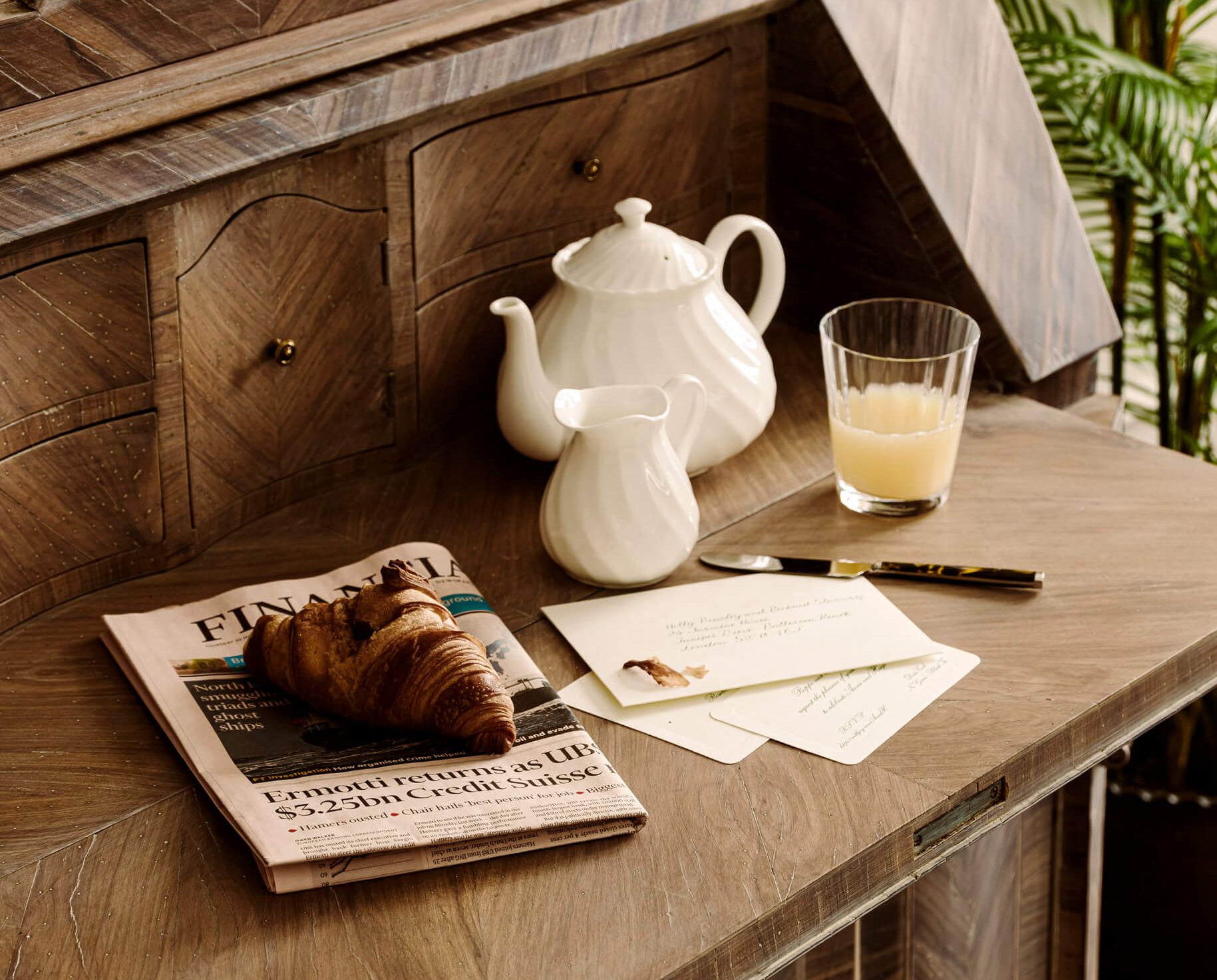 A tea pot and croissant resting on a cabinet.