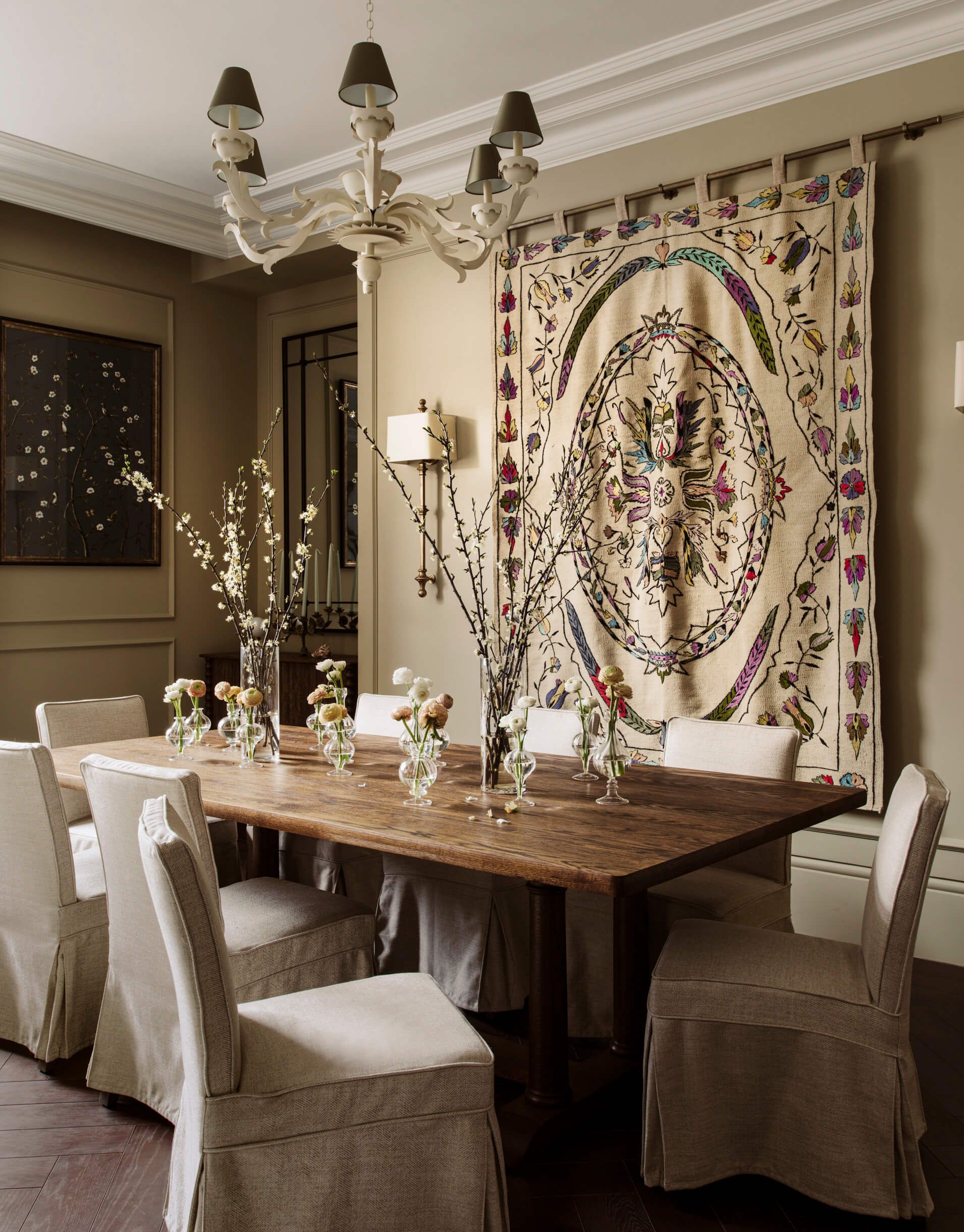 Dining table and chairs with a wall tapestry in the background