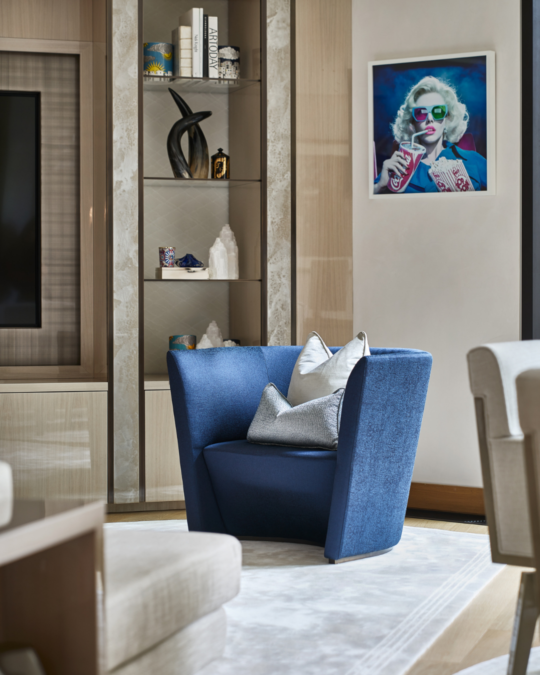 Contemporary living room at One Hyde Park featuring a sculptural blue armchair, custom joinery, curated objects and colourful contemporary artwork.