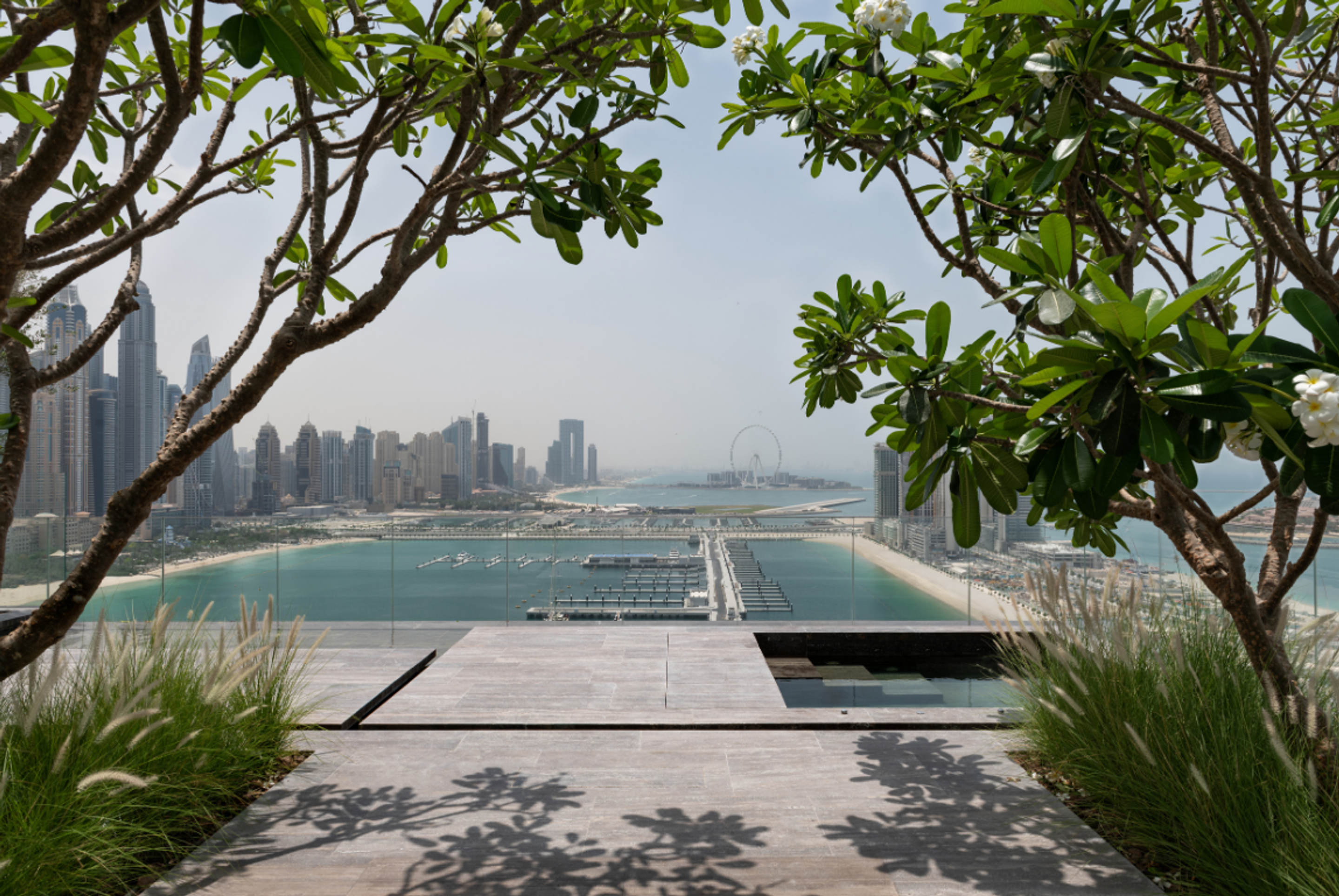 Landscaped terrace overlooking Dubai Marina, framed by mature planting with views across the waterfront and skyline.